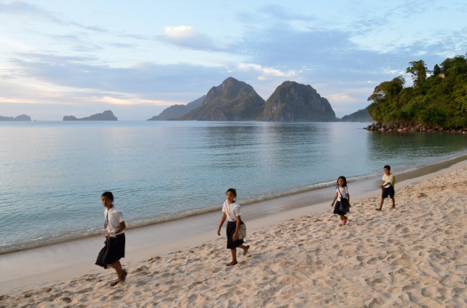 Schoolchildren walk across the beach. 