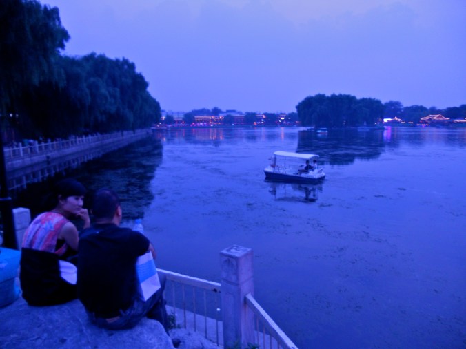 A couple chats at the edge of a lake in Houhai, a popular nightlife destination where many residences have been converted into restaurants and bars. 